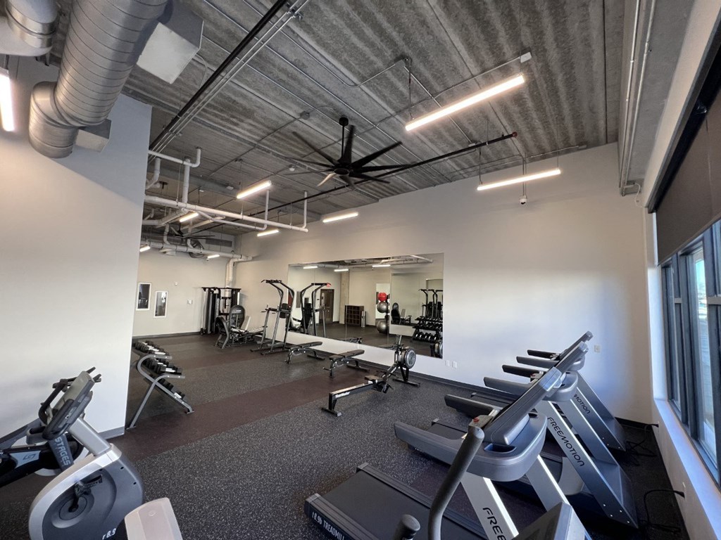 a gym with cardio equipment and weights in a building with white walls