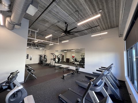 a gym with cardio equipment and weights in a building with white walls