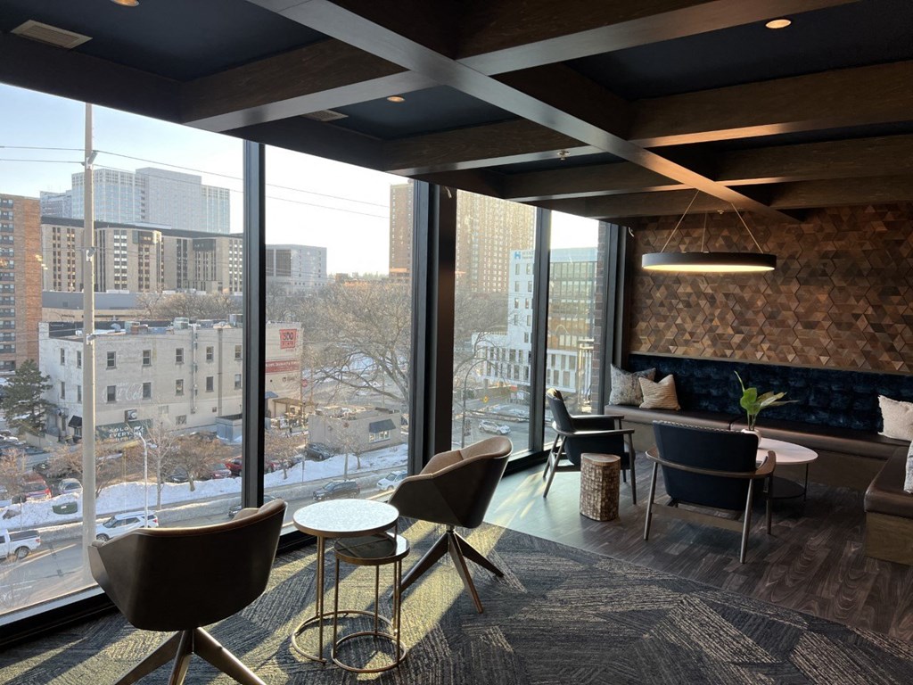 a lounge area with chairs and tables and a large window