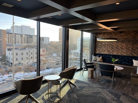 a lounge area with chairs and tables and a large window
