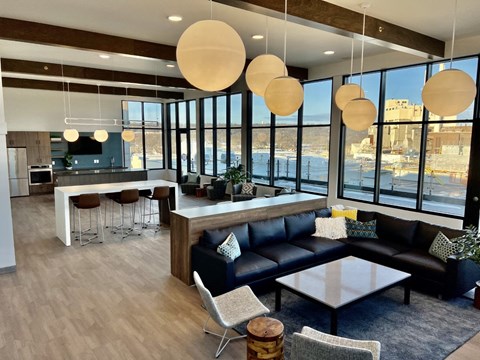 a lounge area with couches and chairs and a kitchen with large windows