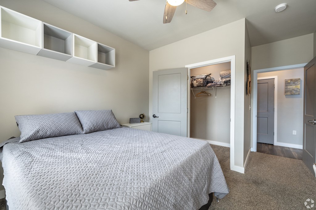 a bedroom with a bed and a closet and a ceiling fan
