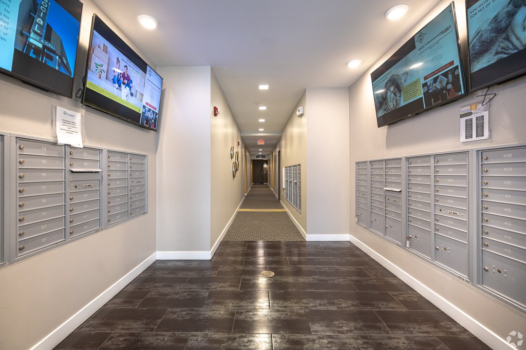 a hallway with mailboxes and televisions in a building
