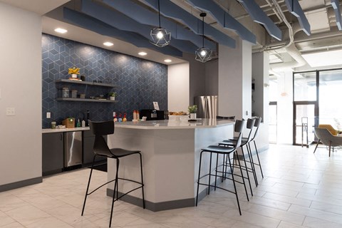 a kitchen with a counter and chairs in a lobby