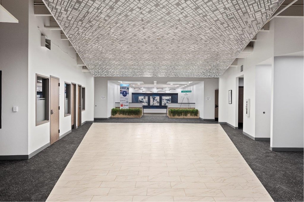 an empty hallway in a building with white walls and tiled floors at The Residences at Tesson Ridge, Saint Louis, 63128