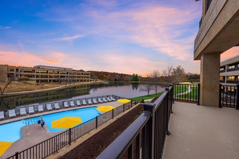 a balcony with a pool and a river at sunset