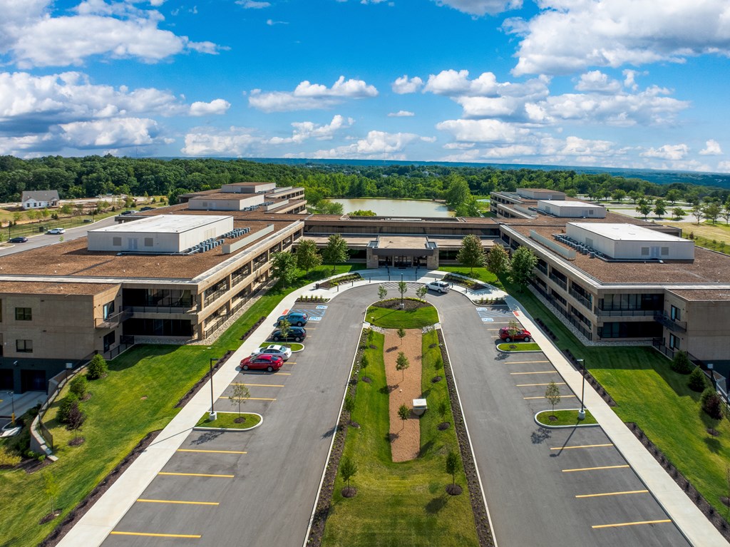 A large, modern building complex with a parking lot in front.