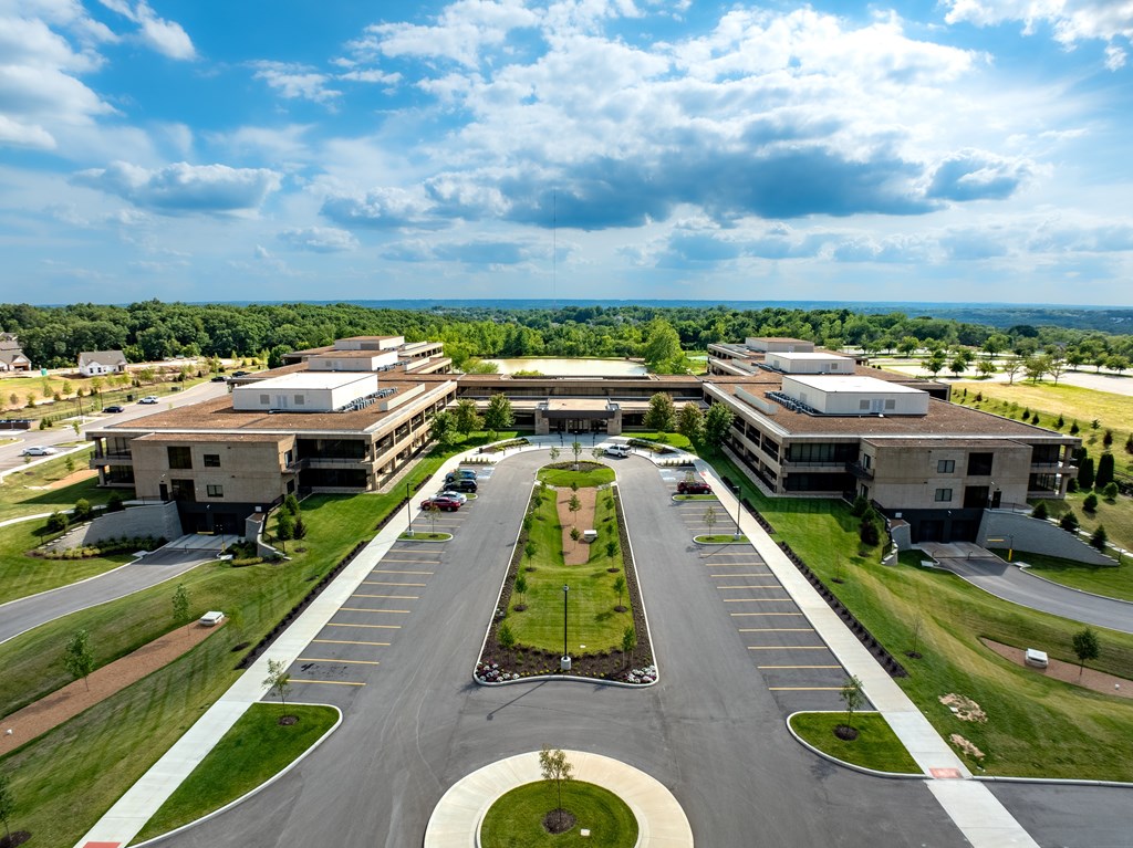 A large, modern building complex with a parking lot in front.