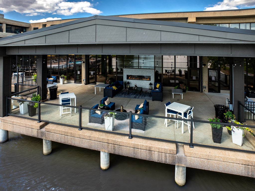 A patio with chairs and tables overlooking a body of water.