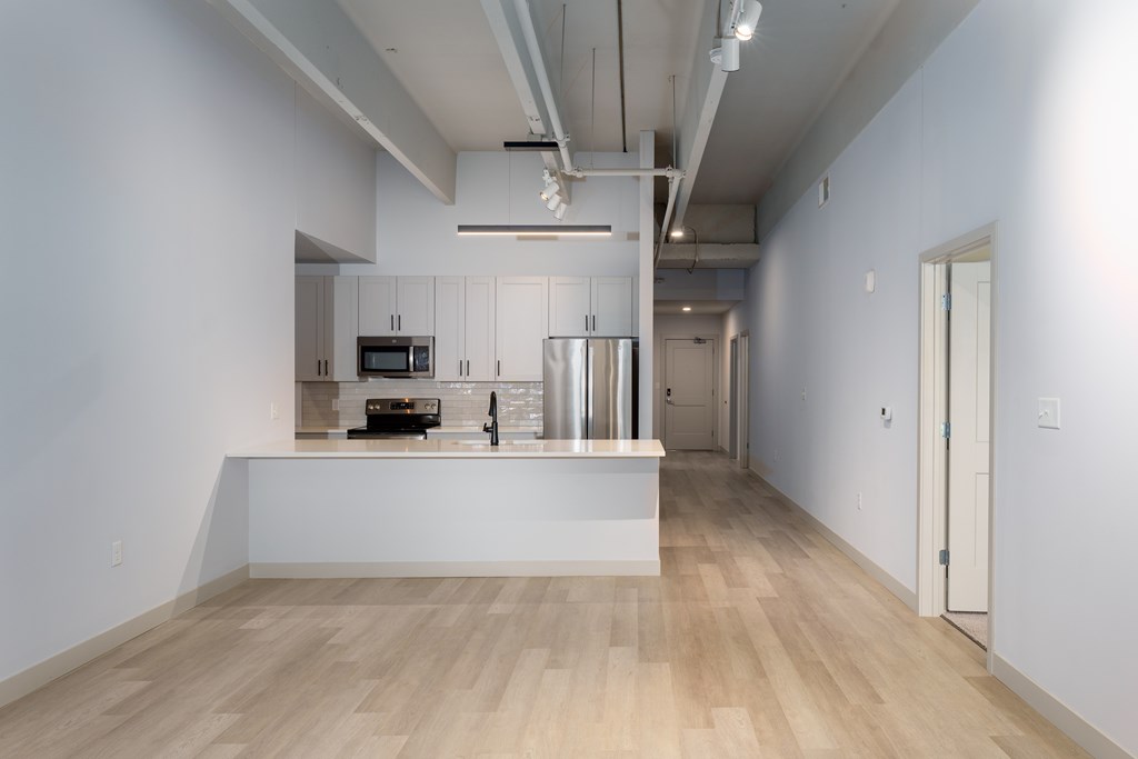 A spacious kitchen with a white countertop and wooden flooring.