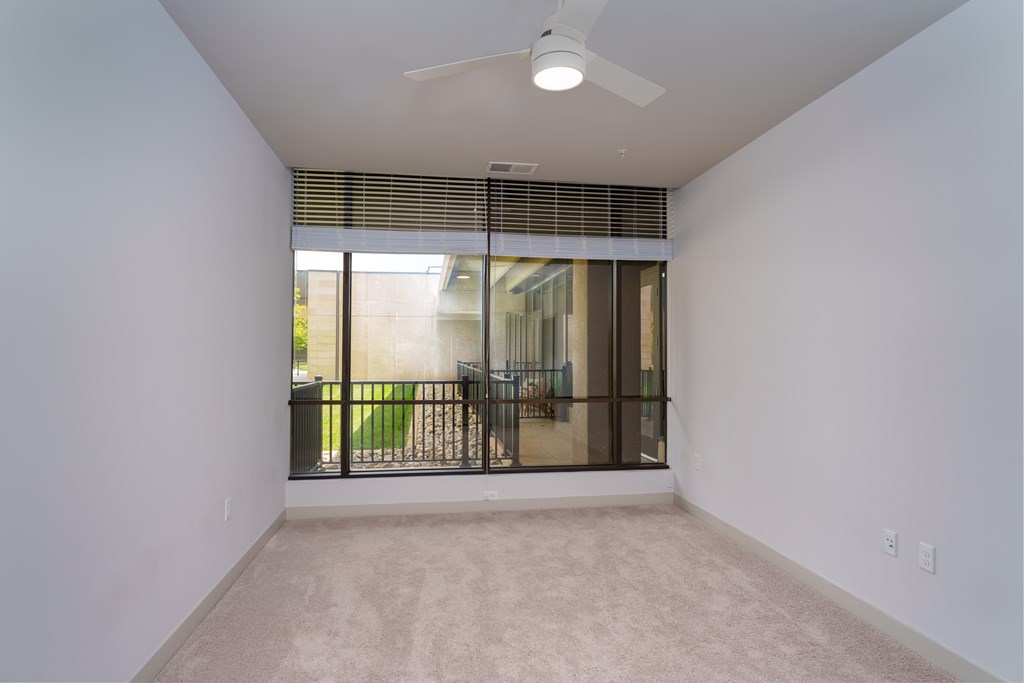 A room with a ceiling fan and a window with blinds.