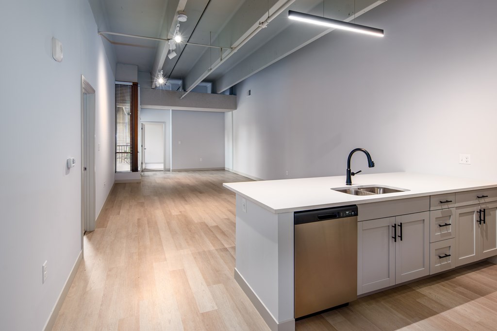 A modern kitchen with a white countertop and stainless steel appliances.