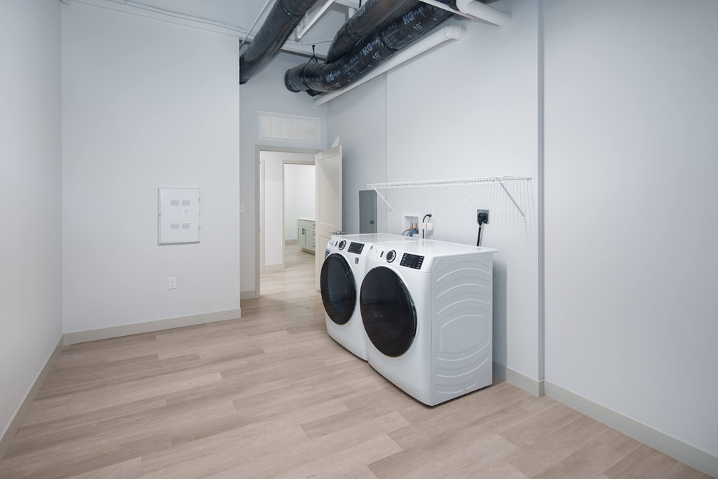 A white washing machine is in a room with wooden floors.