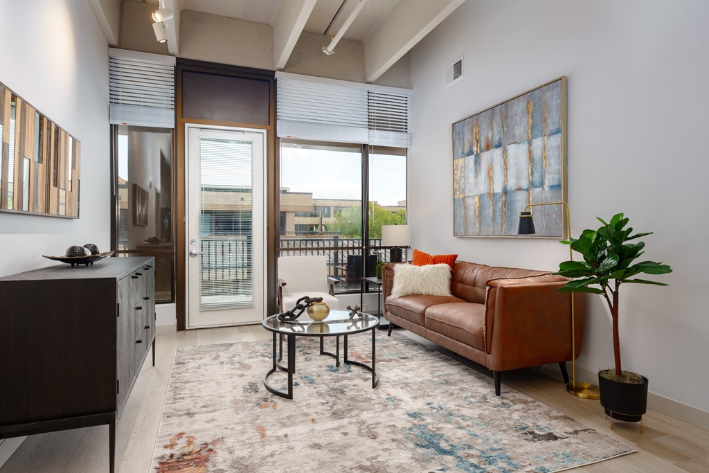 A living room with a brown couch, a coffee table, and a large painting on the wall.