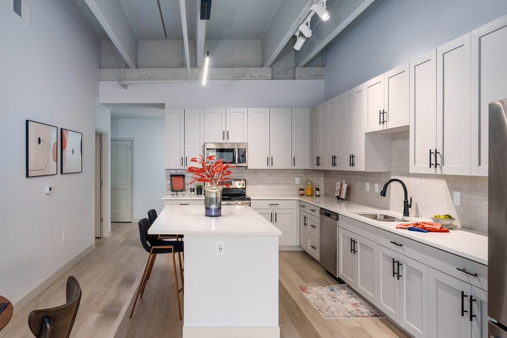 A kitchen with white cabinets and a white island.
