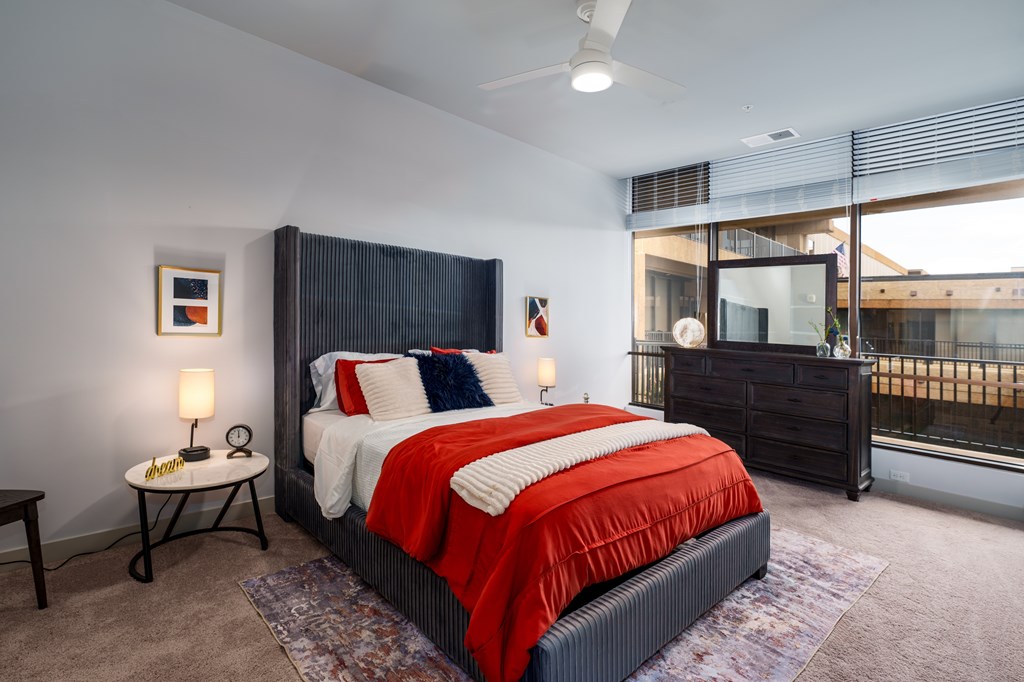A bedroom with a large bed and a window overlooking a balcony.