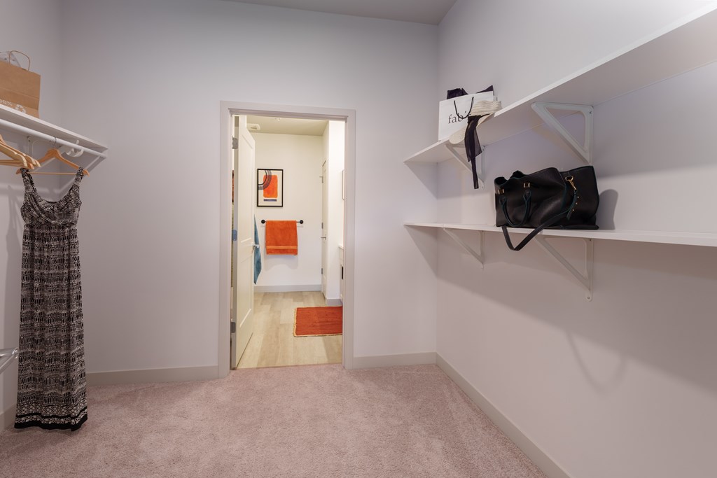 A room with a door and a wall-mounted shelf with a bag on it.