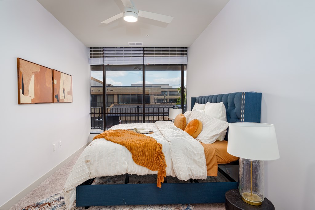 A bedroom with a bed, a lamp, and a painting on the wall.