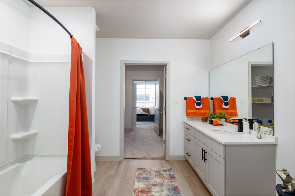 A bathroom with a white vanity and a red shower curtain.
