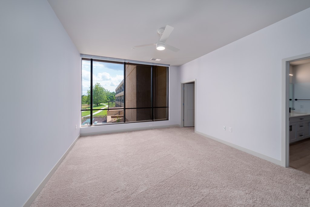 A large empty room with a window overlooking a building.