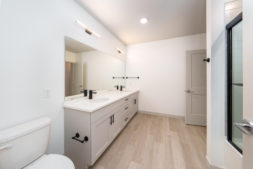 A white bathroom with a wooden floor and a white toilet.