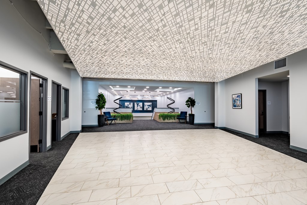 A hallway with a tiled ceiling and a bench with a blue cushion.