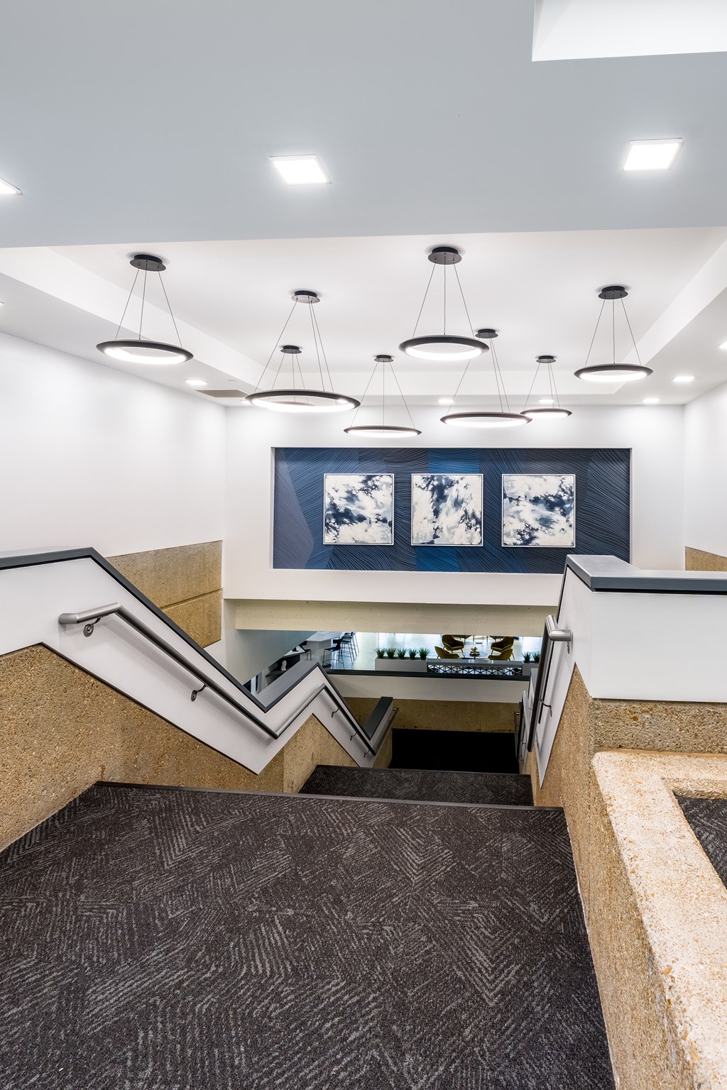 A staircase with a carpeted runner and a wall-mounted light fixture above it.