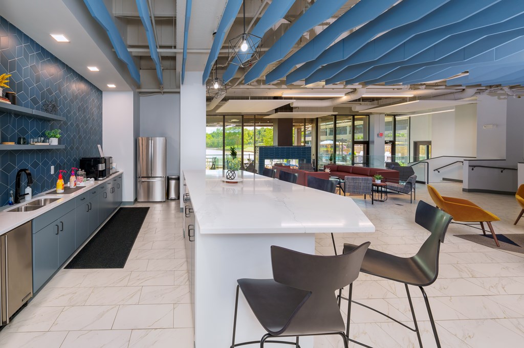 A modern kitchen with a white island and black chairs.