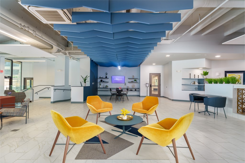 A modern living room with a blue ceiling and yellow chairs.