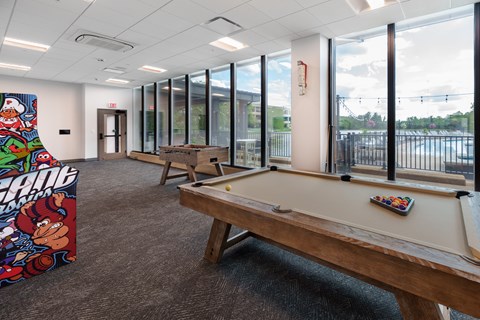 A billiard table in a room with a pool table poster on the wall. at The Residences at Tesson Ridge Apartments, Missouri