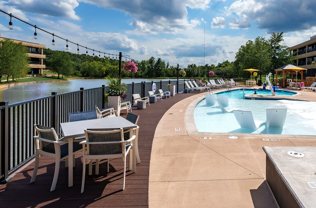 A poolside area with chairs and tables overlooking a pool.