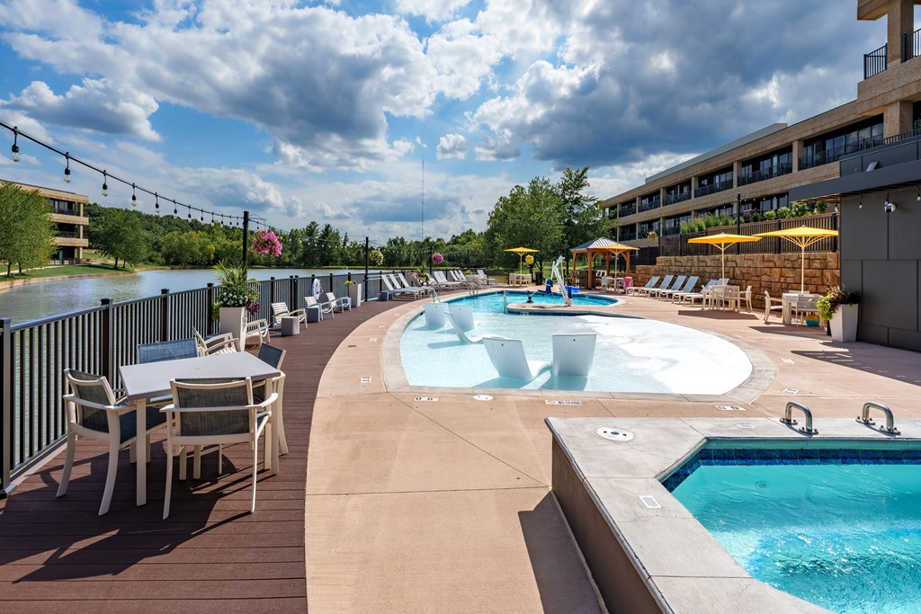 A large outdoor pool area with a hot tub and lounge chairs.