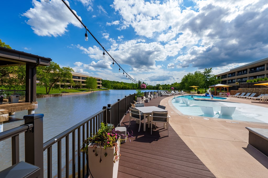 A pool area with a hot tub and a view of a river.