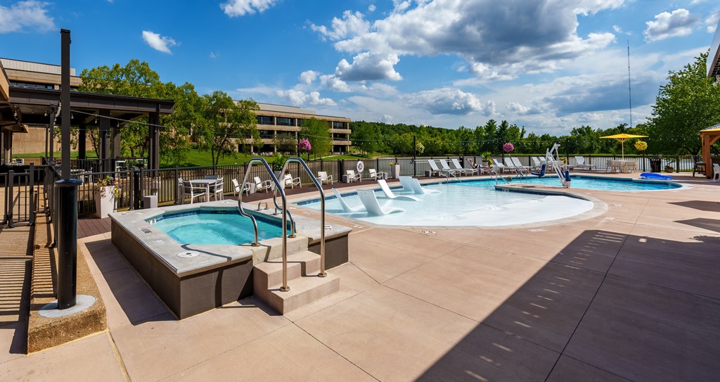 A large outdoor swimming pool with a hot tub and a water slide.