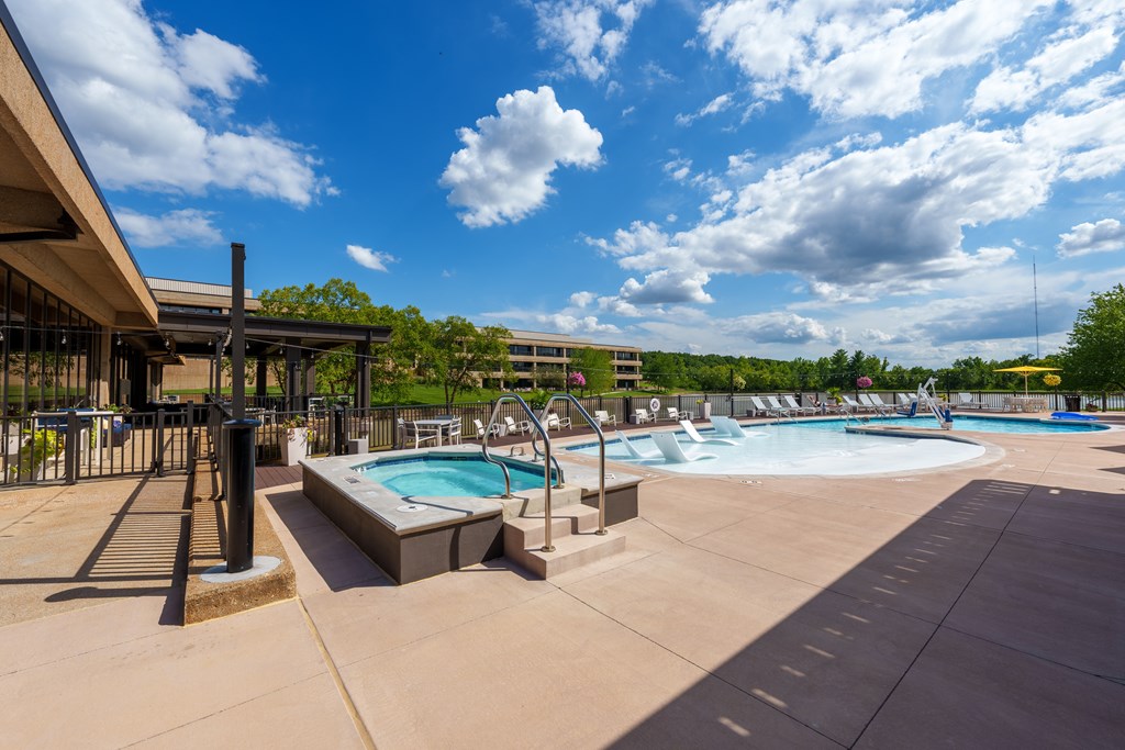 A large outdoor swimming pool with a hot tub and a water slide.