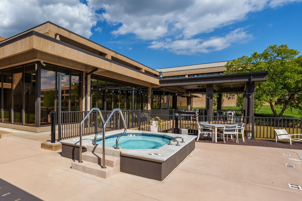 A hot tub is in the middle of a patio with a table and chairs.