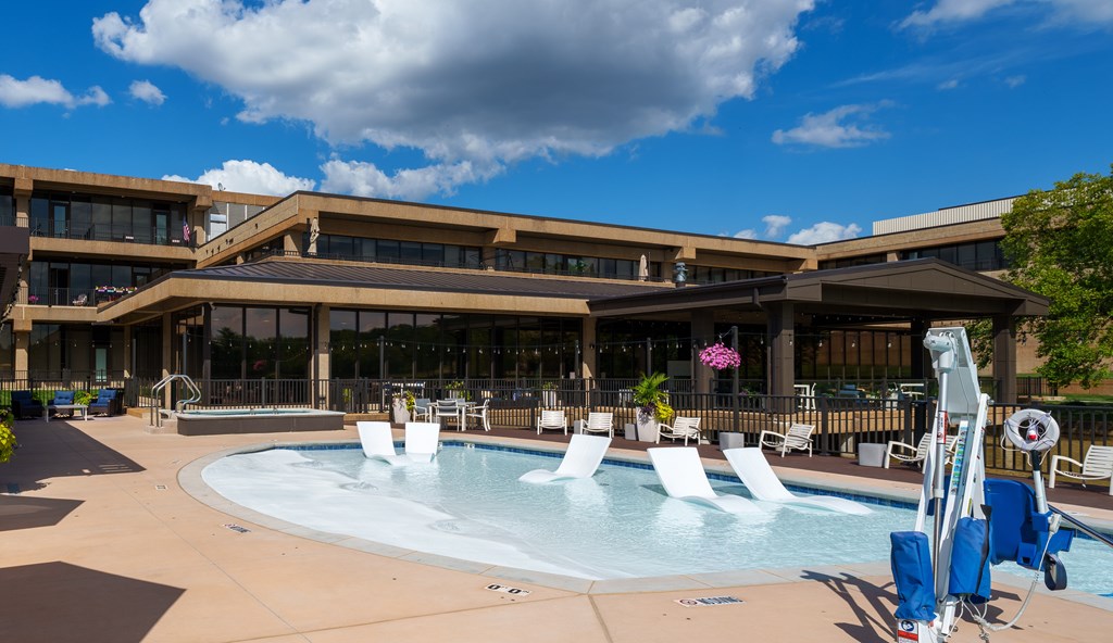 A large outdoor swimming pool with loungers and a building in the background.