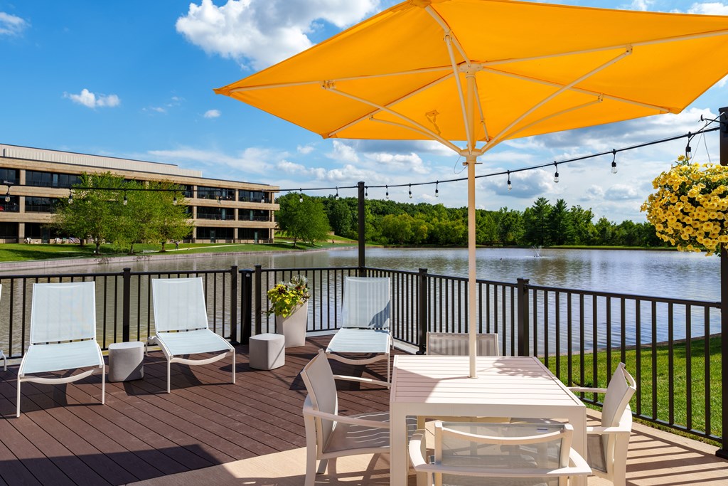 A yellow umbrella is on a patio table with chairs.