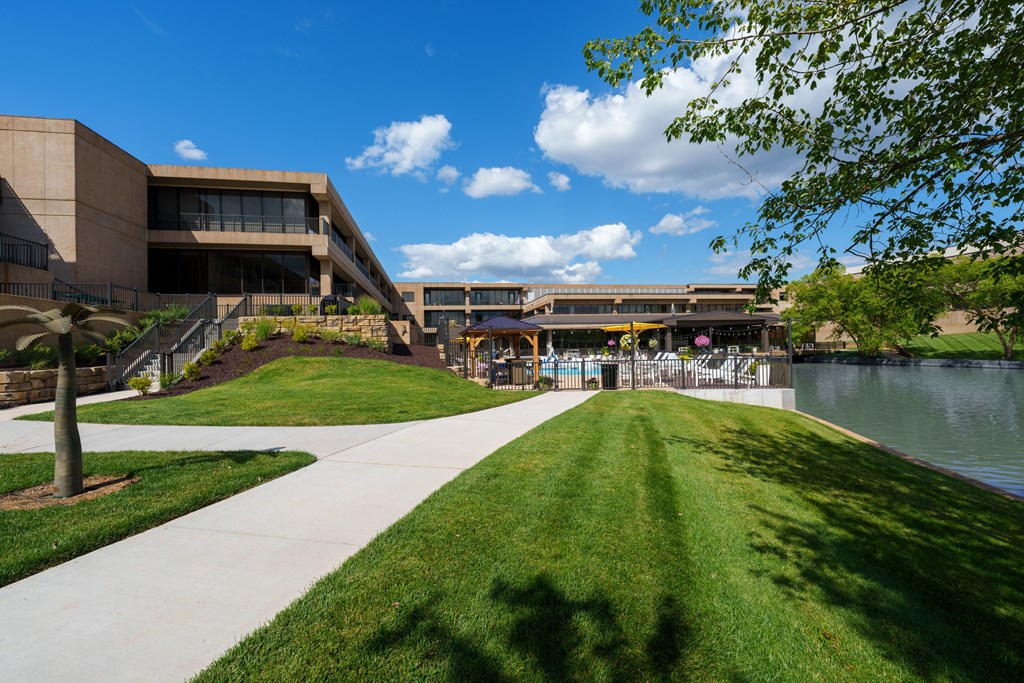 A walkway with a grassy area and a body of water in front of a building.
