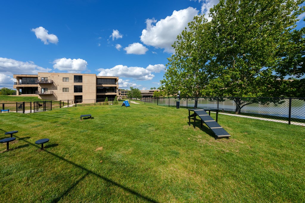 A grassy field with picnic tables and a building in the background.