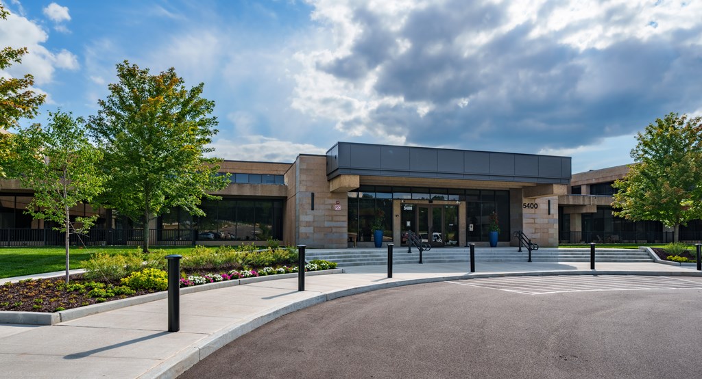 A modern building with a grey roof and a glass entrance.