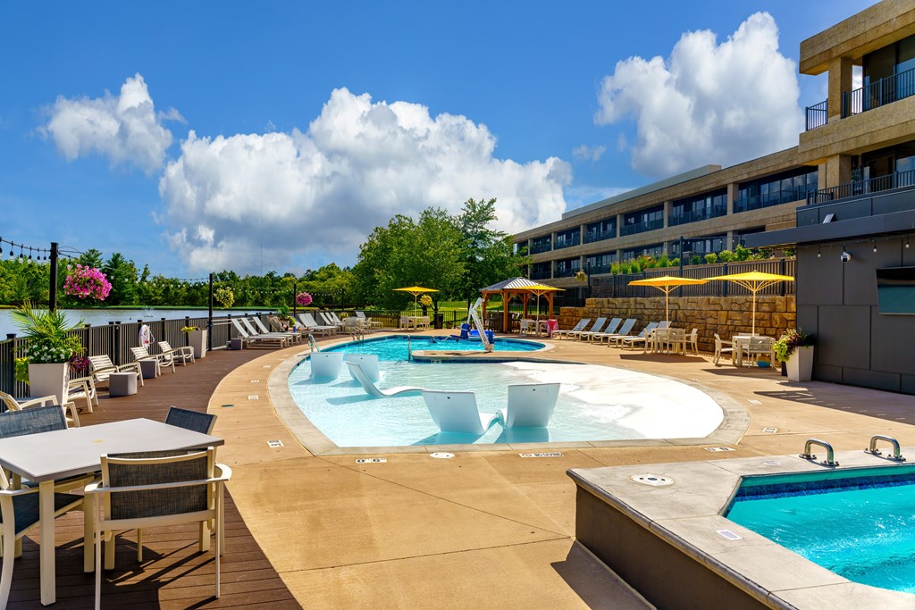 A large outdoor pool area with a hot tub and lounge chairs.