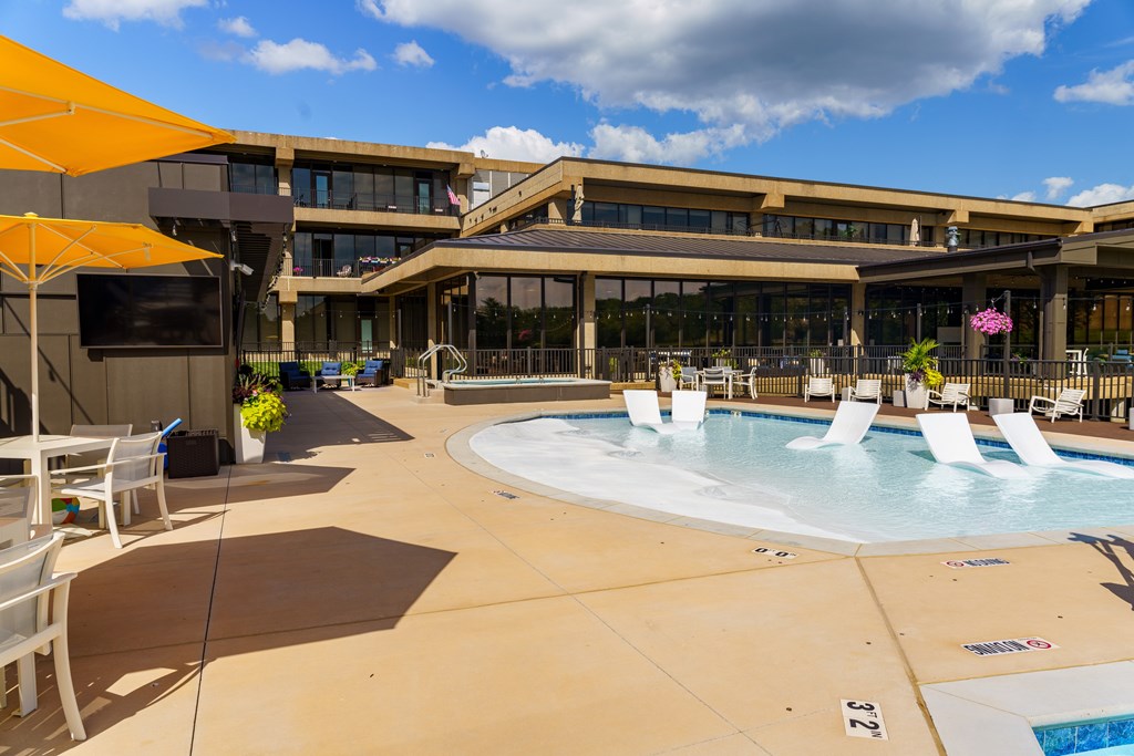 A large outdoor pool area with sun loungers and a building in the background.