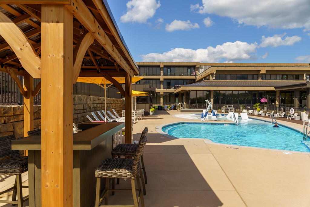 A pool area with a wooden structure and chairs.
