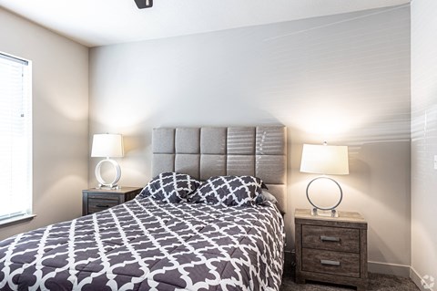 a bedroom with a bed and two lamps and a window at Trinity Woods Apartments, Independence, MO, 64015