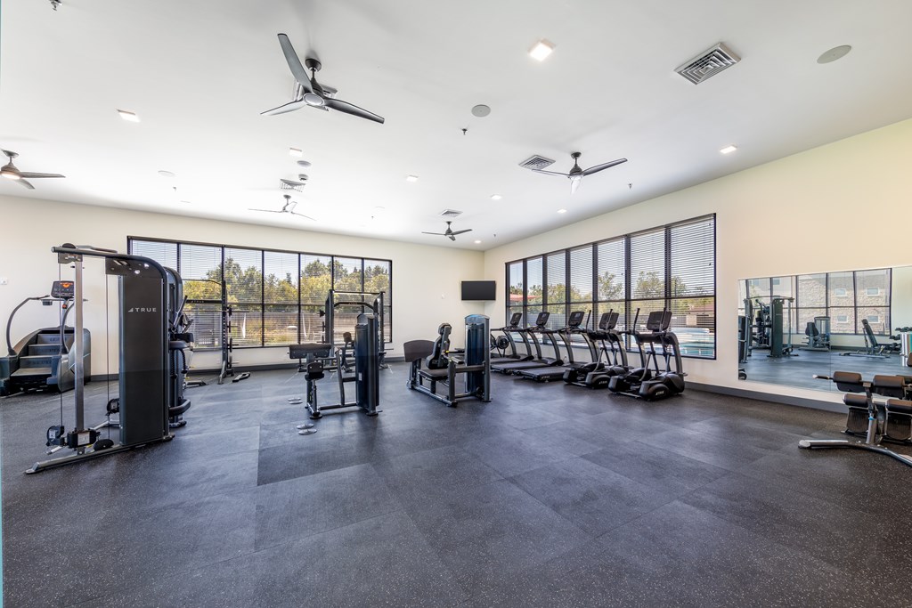 A spacious gym with various exercise equipment and a large window.