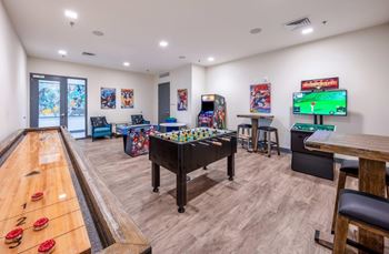 A room with a pool table, a foosball table, a pinball machine, and a video game setup.