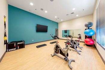 A gym with exercise equipment and a television on the wall.