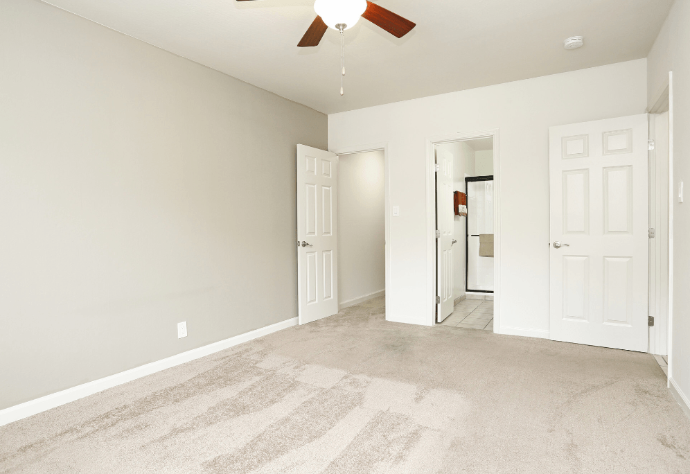a bedroom with two doors and a ceiling fan