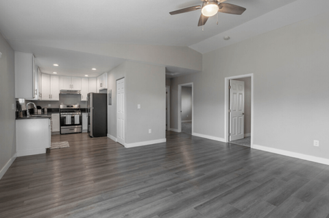 an empty living room and kitchen with a ceiling fan